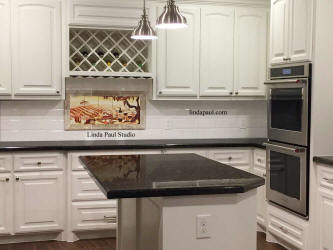 black and white kitchen with wine tile mural above stove